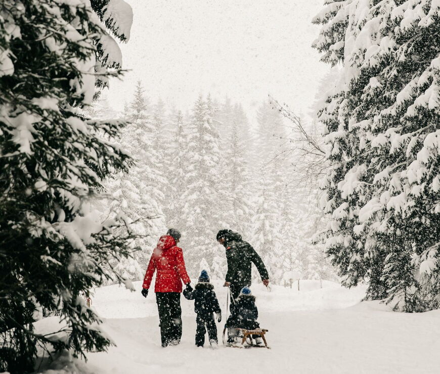 Familie mit Rodel beim Winterurlaub